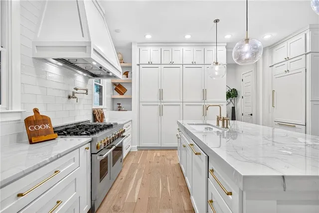 a kitchen with stainless steel appliances kitchen island granite countertop a table chairs and a wooden floor