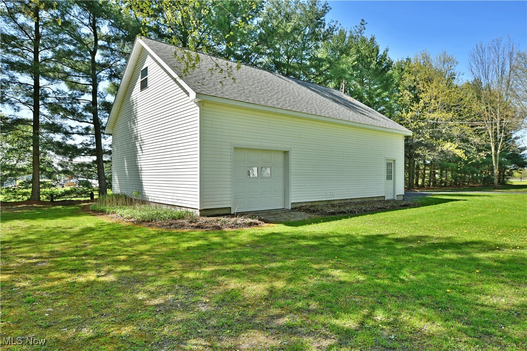379 Housel Craft Road Bristolville, OH 44402 - Photo 9 of 50 View of home's exterior with a yard, roof with shingles, and a detached garage