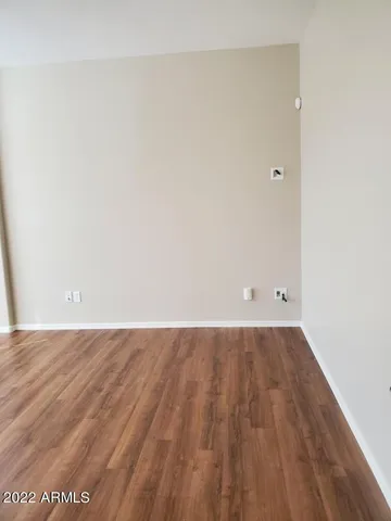 an empty room with wooden floor chandelier and windows