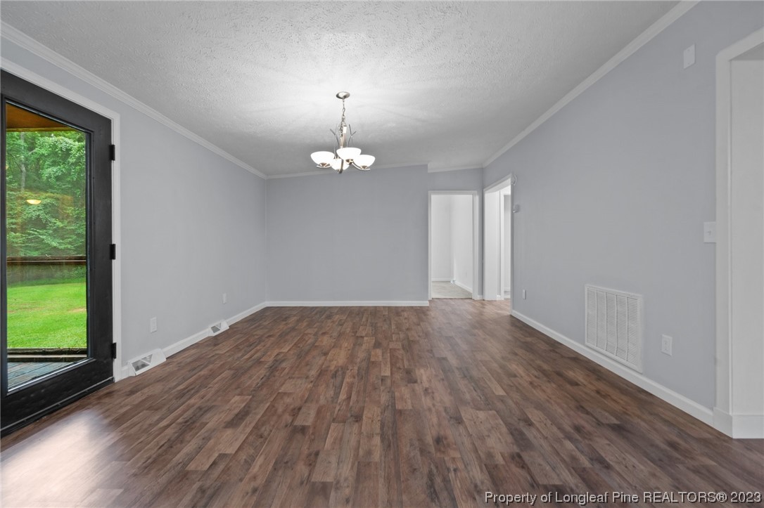 287 Doyle Cox Road Sanford, NC 27330 - Photo 10 of 35 an empty room with wooden floor chandelier and windows