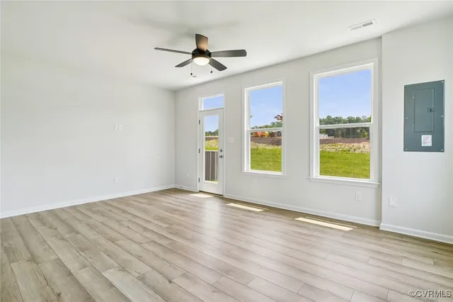 a view of empty room with wooden floor and fan