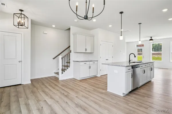 a kitchen with stainless steel appliances granite countertop a sink a stove a refrigerator and island with wooden floor