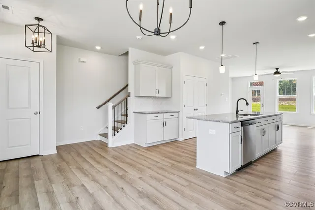 a kitchen with stainless steel appliances granite countertop a sink a stove a refrigerator and island with wooden floor