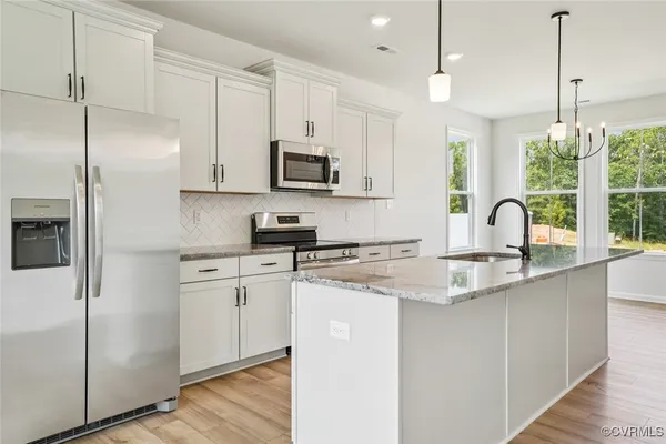 a kitchen with stainless steel appliances granite countertop a sink a stove a refrigerator a center island with wooden floor and cabinets