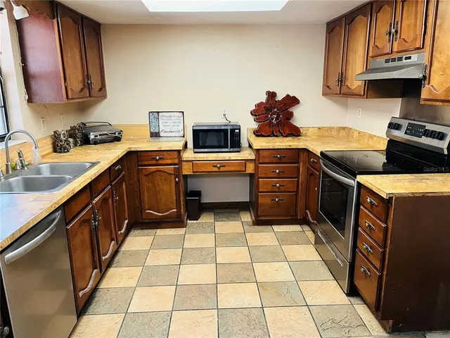 a kitchen with stainless steel appliances a stove a sink and a microwave
