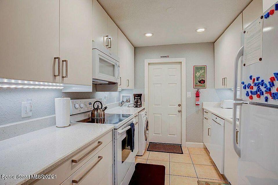 411 Audubon Drive Melbourne, FL 32901 - Photo 39 of 47 a kitchen with white cabinets and white appliances