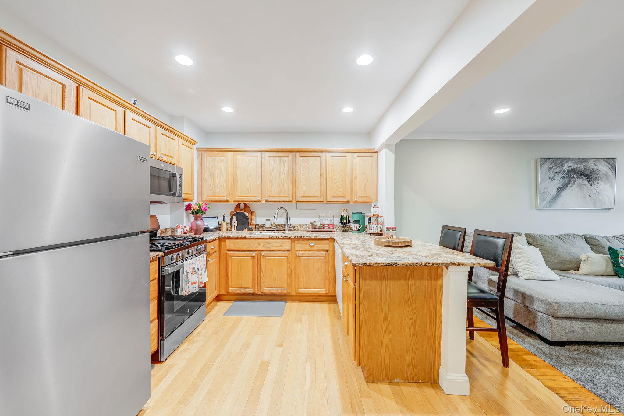 124 Smith Street, Unit 3F Freeport, NY 11520 - Photo 15 of 15 Kitchen with open floor plan, appliances with stainless steel finishes, light brown cabinetry, a peninsula, and light stone counters