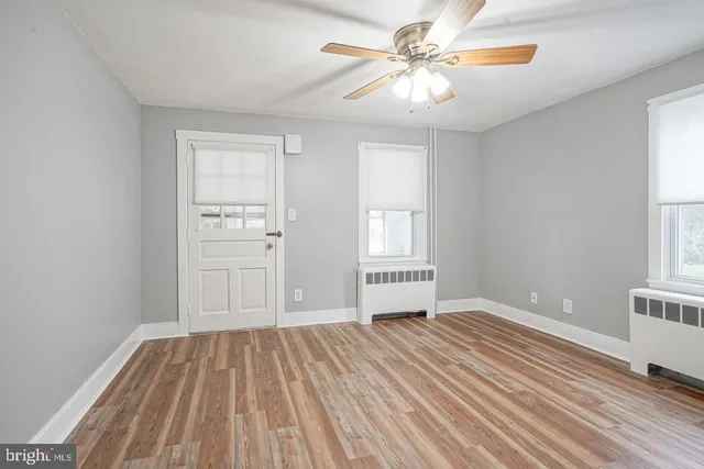 a view of empty room with wooden floor and fan