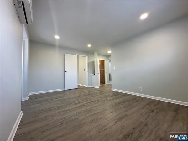 an empty room with wooden floor and stainless steel appliances