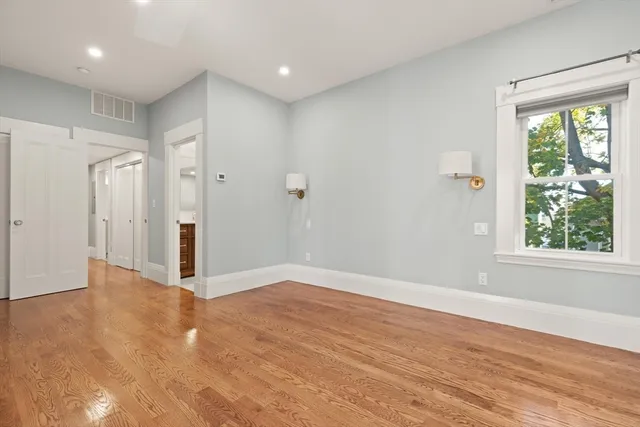 a view of an empty room with wooden floor and a window