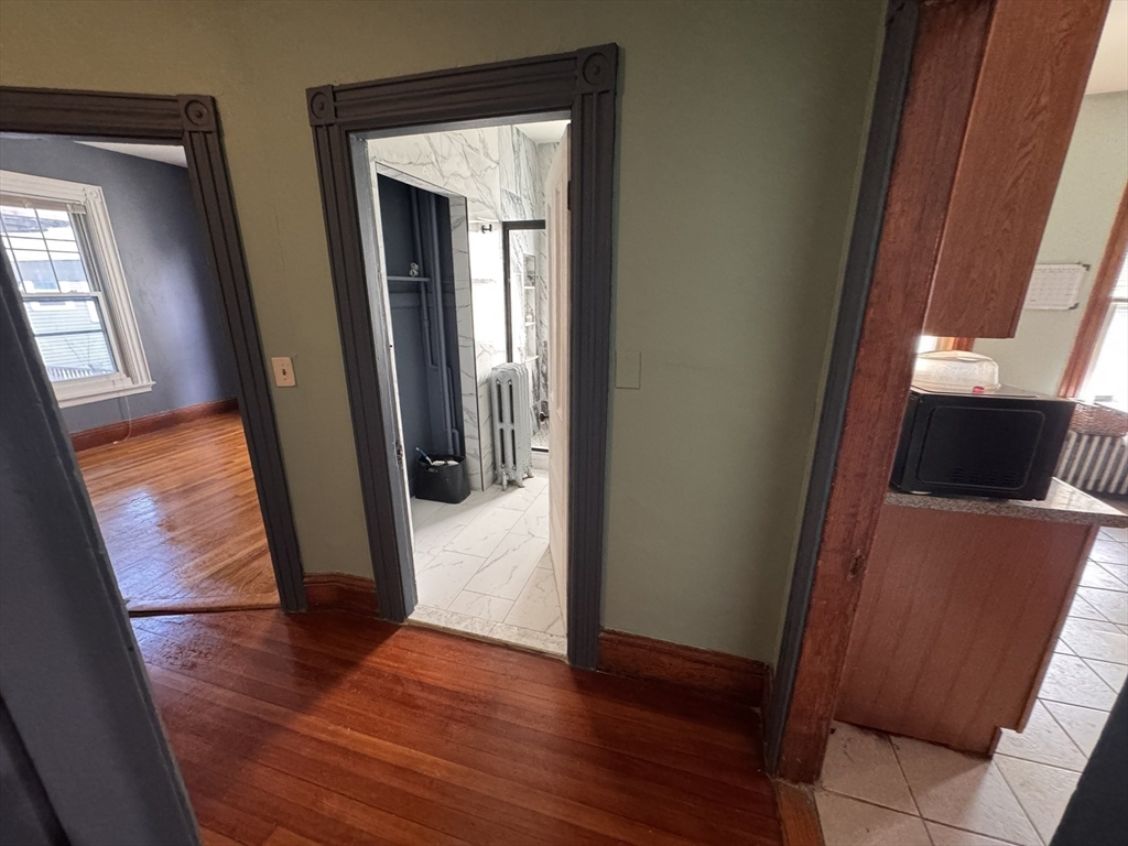 472 Warren Street Boston, MA 02121 - Photo 21 of 42 a view of a hallway with wooden floor and glass door