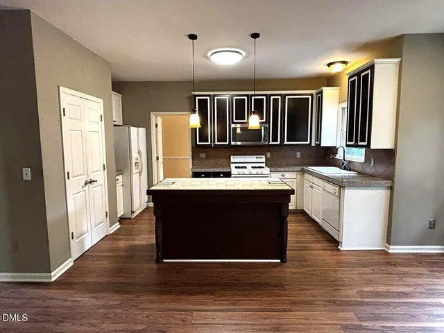a living room with stainless steel appliances kitchen island granite countertop a stove and a refrigerator