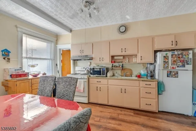 a kitchen with stainless steel appliances kitchen island granite countertop a refrigerator a stove a sink dishwasher and white cabinets with wooden floor