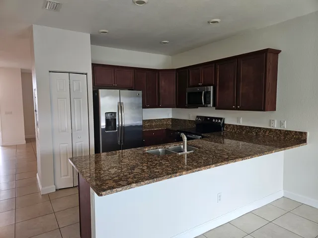 a kitchen with granite countertop a sink a counter top space appliances and cabinets