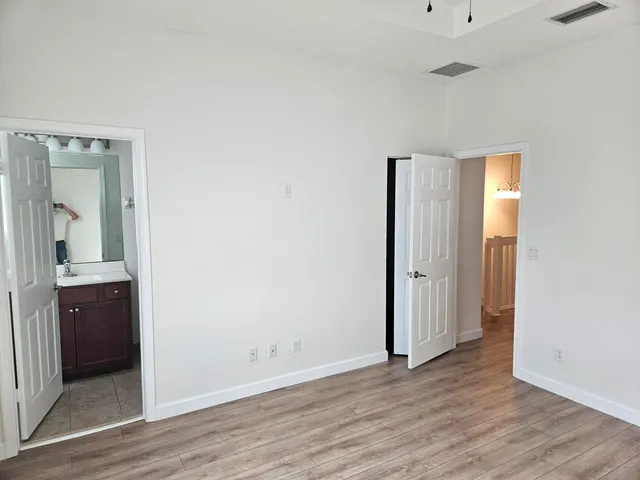 an empty room with wooden floor and mirror