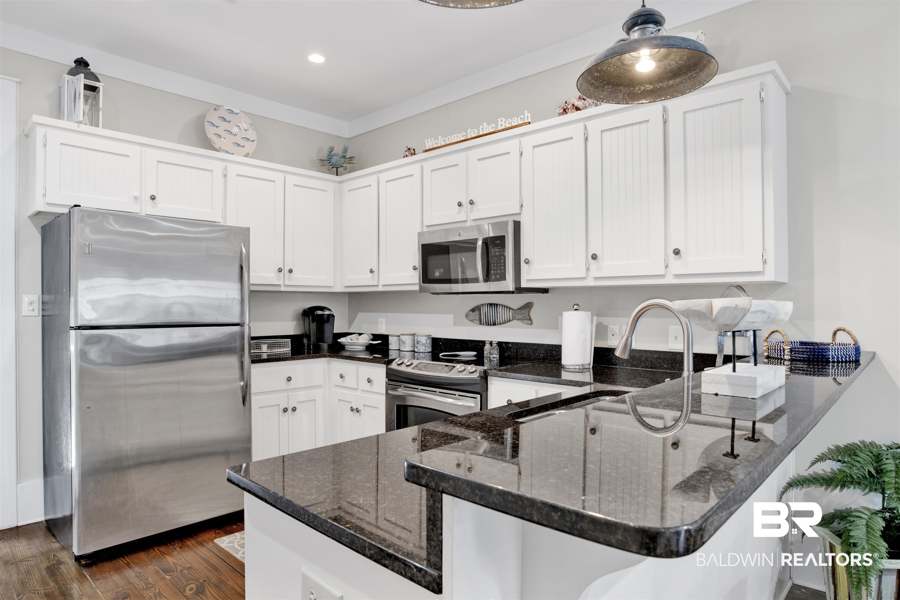 25773 Canal Road, Unit 38 Orange Beach, AL 36561 - Photo 6 of 38 Kitchen featuring white cabinetry, kitchen peninsula, dark stone countertops, stainless steel appliances, and dark hardwood / wood-style flooring