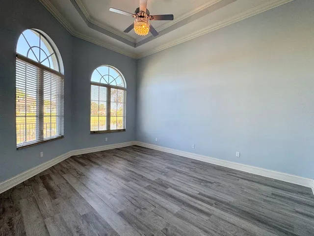 an empty room with wooden floor fan and windows