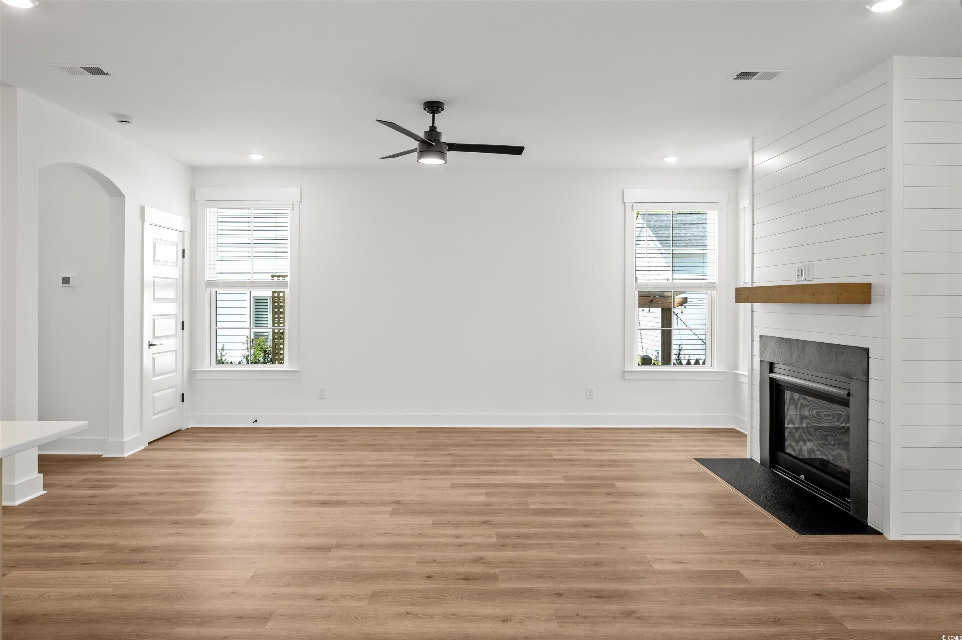 67 Bridge View Road Georgetown, SC 29440 - Photo 11 of 40 Unfurnished living room with recessed lighting, a fireplace with flush hearth, light wood-style floors, arched walkways, and a ceiling fan
