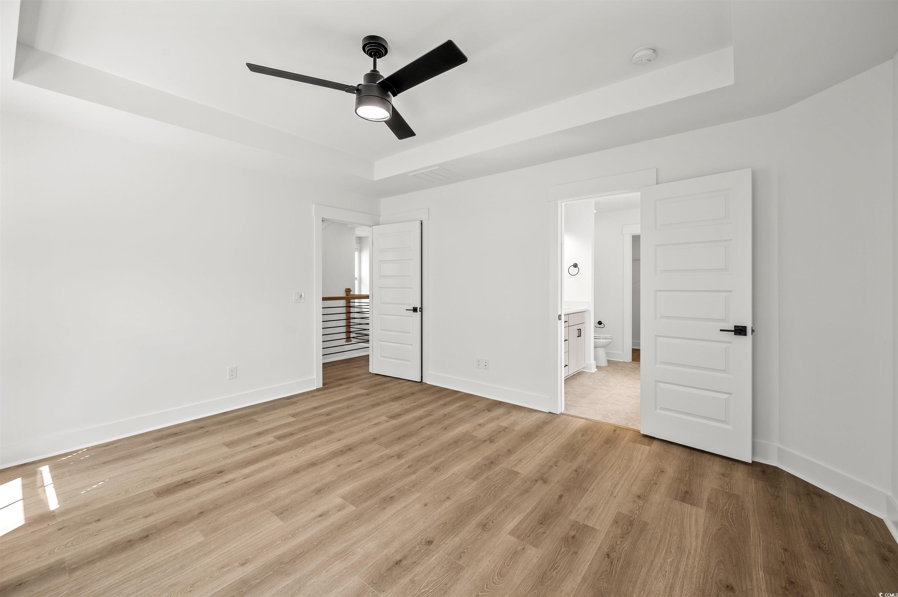 67 Bridge View Road Georgetown, SC 29440 - Photo 19 of 40 Unfurnished bedroom featuring a tray ceiling, light wood-style floors, ceiling fan, and connected bathroom