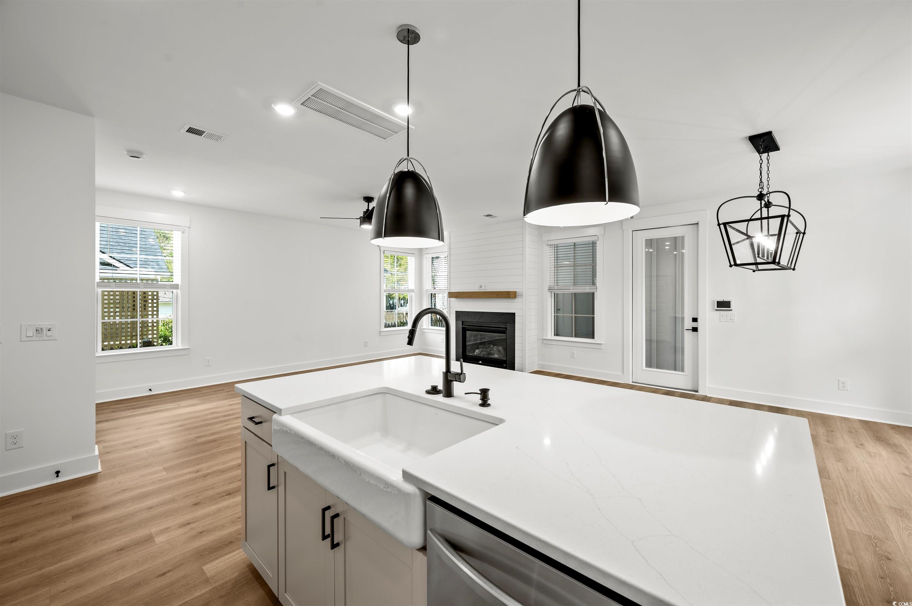 67 Bridge View Road Georgetown, SC 29440 - Photo 40 of 40 Kitchen with a glass covered fireplace, an island with sink, hanging light fixtures, open floor plan, and light wood-style flooring