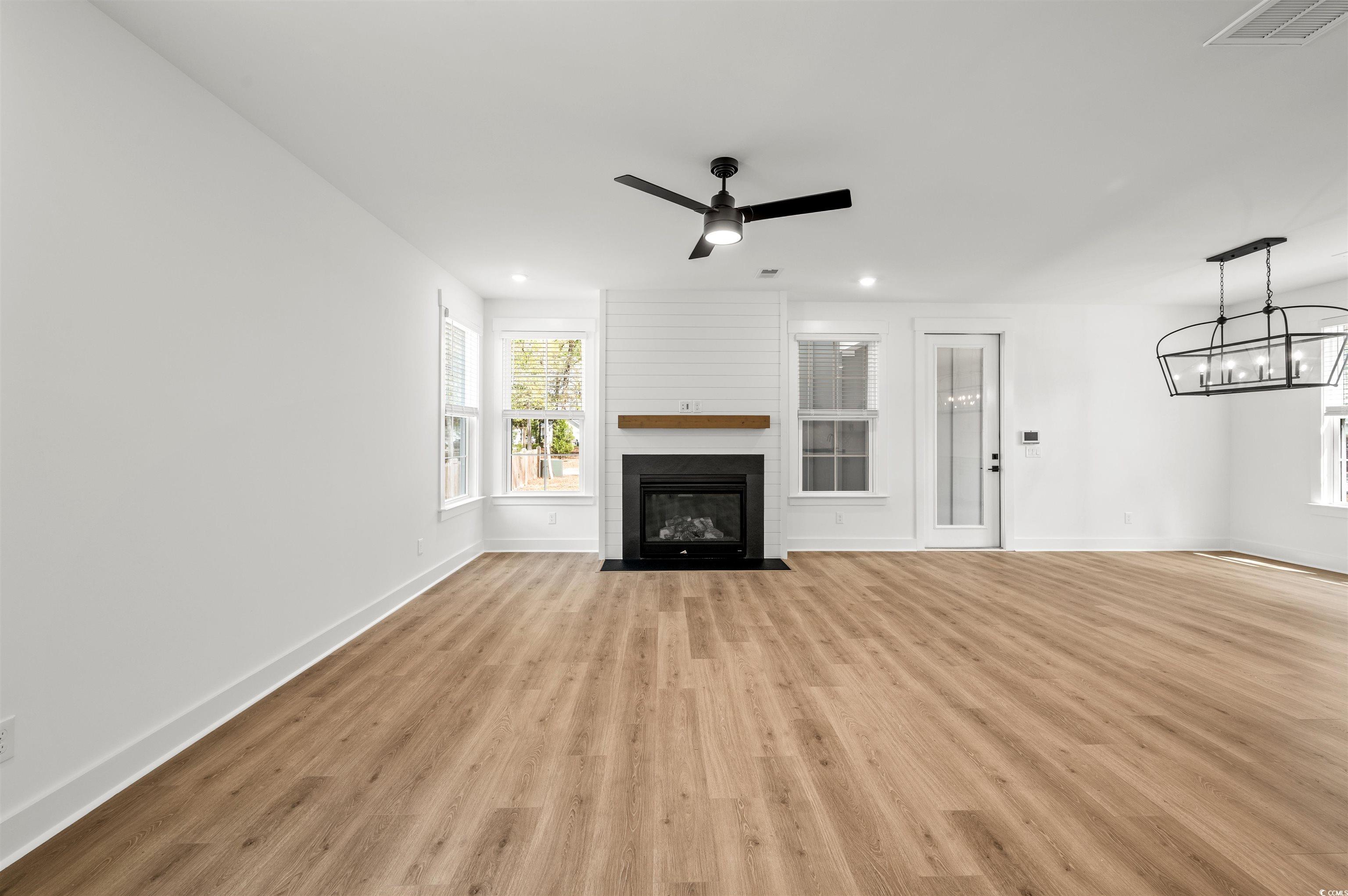 67 Bridge View Road Georgetown, SC 29440 - Photo 9 of 40 Unfurnished living room with ceiling fan, a fireplace, light wood-type flooring, recessed lighting, and a chandelier