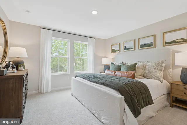a spacious bedroom with a bed and a dresser next to a window