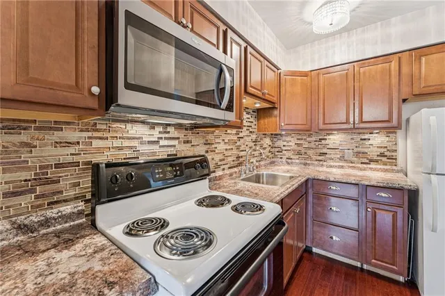 a kitchen with granite countertop a sink stove and microwave