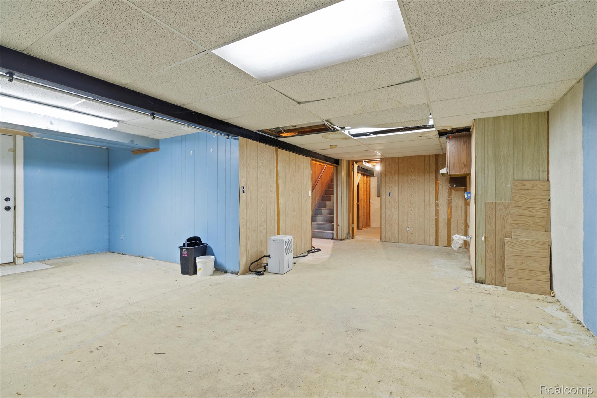 309 Windy Bluff Street Flushing, MI 48433 - Photo 24 of 32 Spacious lower level featuring a drop ceiling, exposed structural beam, fluorescent lighting, and a partially finished wall with vertical paneling
