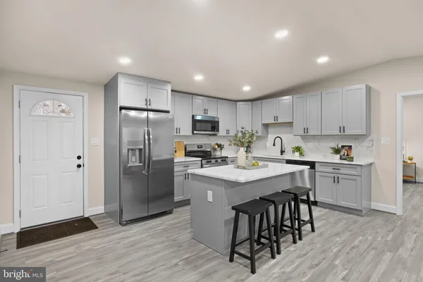a kitchen with stainless steel appliances granite countertop a refrigerator a sink dishwasher a stove and white countertops with wooden floor