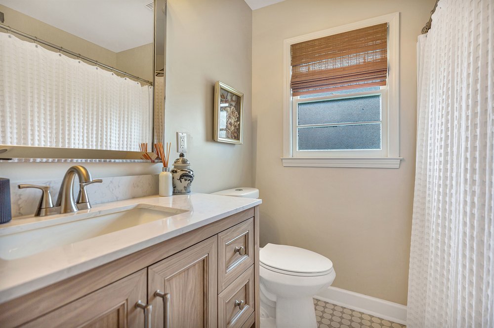 2310 Hannah Road Anderson, SC 29621 - Photo 18 of 32 A well-appointed bathroom features a light wood vanity with a white countertop and a window for natural illumination.