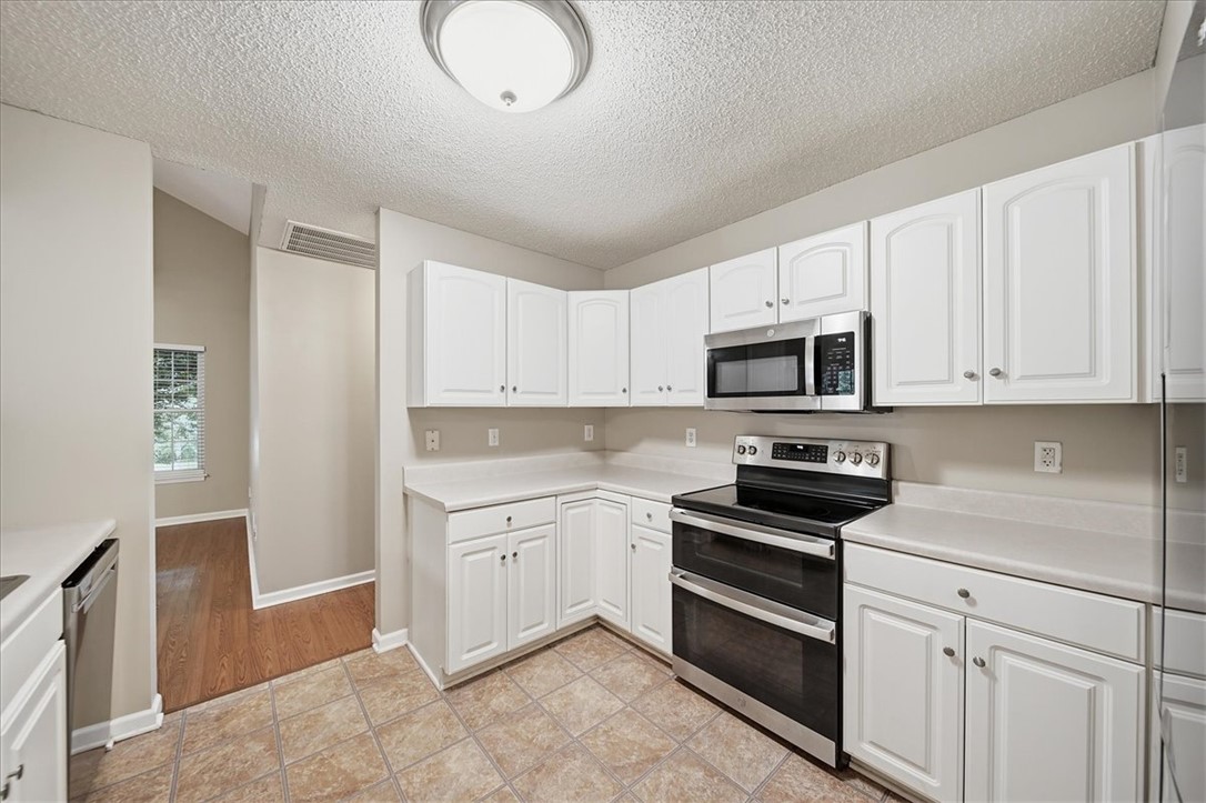 101 Grand Oak Circle Pendleton, SC 29670 - Photo 12 of 40 A well-equipped kitchen features white cabinetry, sleek appliances, and tile flooring, ready for culinary endeavors.