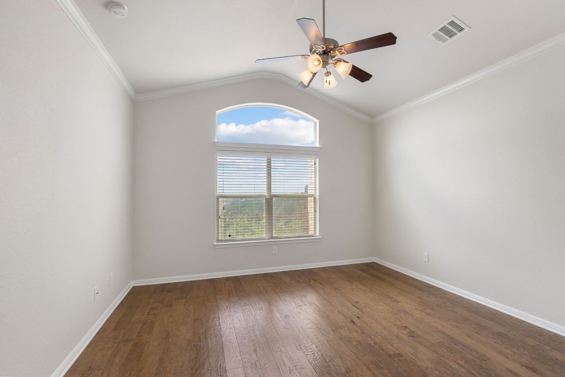 9617 Solana Vista Loop, Unit A Austin, TX 78750 - Photo 23 of 35 an empty room with wooden floor chandelier fan and windows