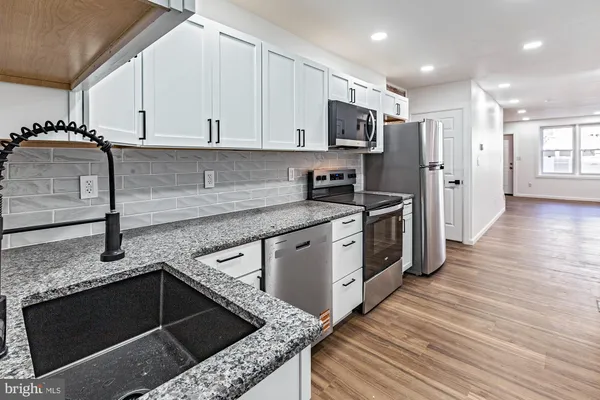 a kitchen with stainless steel appliances granite countertop a stove a sink and a refrigerator