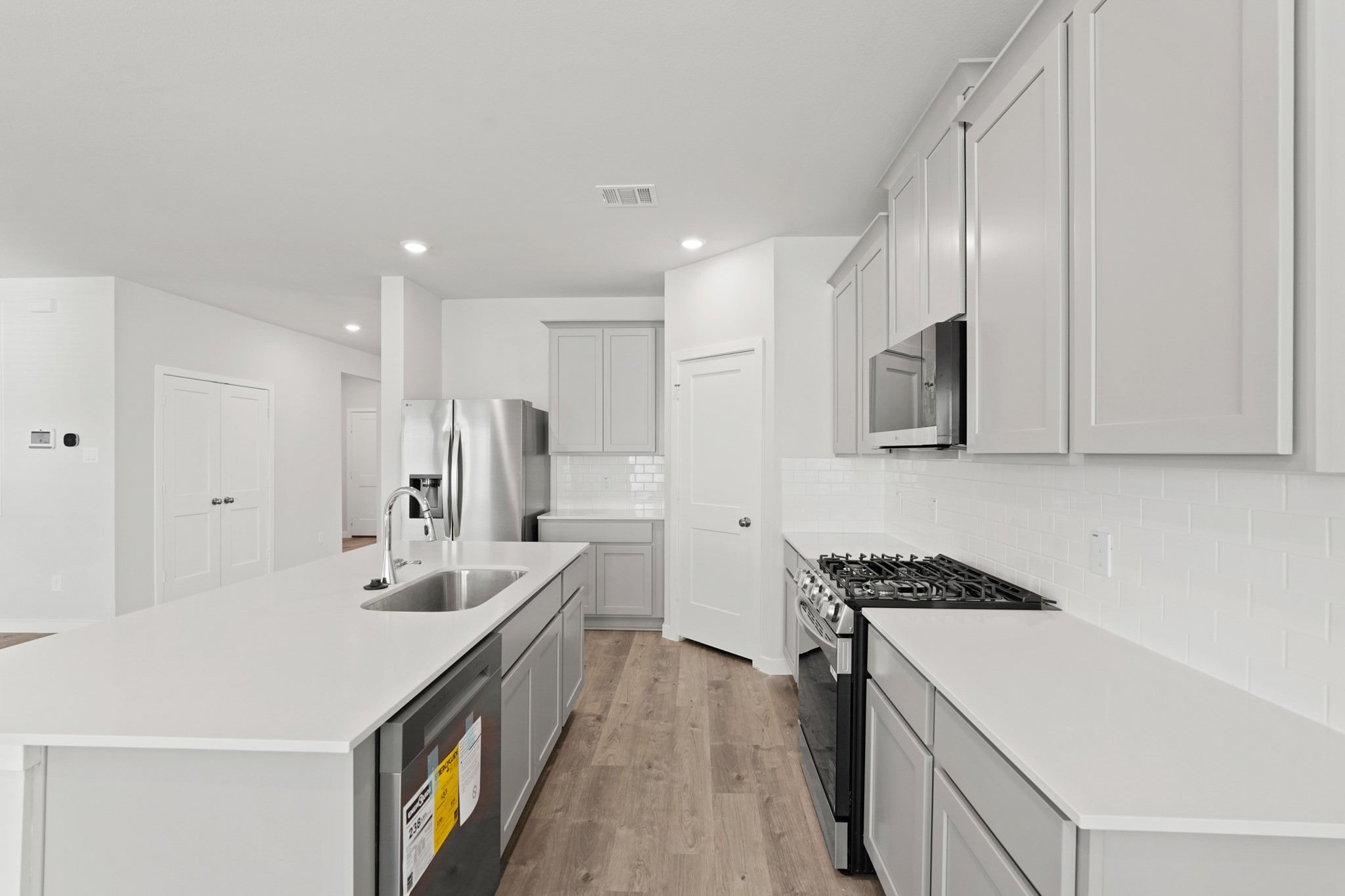 112 Water Grass Trail Clute, TX 77531 - Photo 7 of 36 a large white kitchen with stainless steel appliances lots of counter space and wooden floor