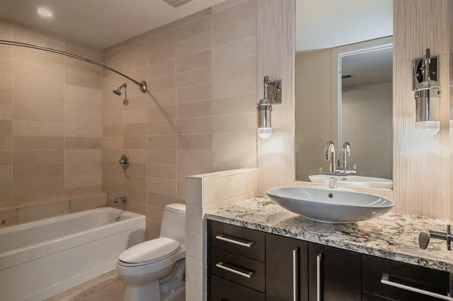 a bathroom with a granite countertop sink a toilet and bathtub