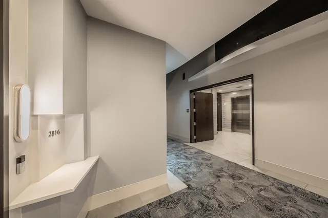 a view of a hallway with wooden floor and a bathroom