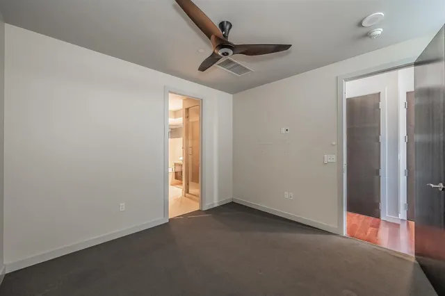 an empty room with a ceiling fan and window