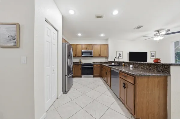 a large kitchen with stainless steel appliances granite countertop a stove top oven a refrigerator a sink and a microwave