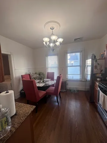 a dining room filled chandelier and wooden floor