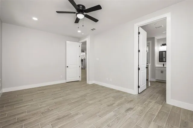an empty room with wooden floor and ceiling fan