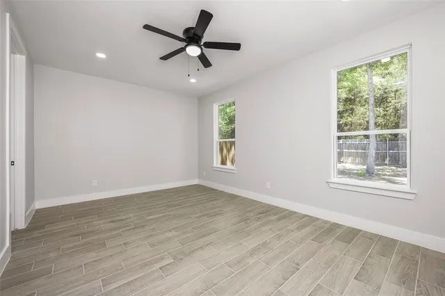 a view of an empty room with a window and wooden floor