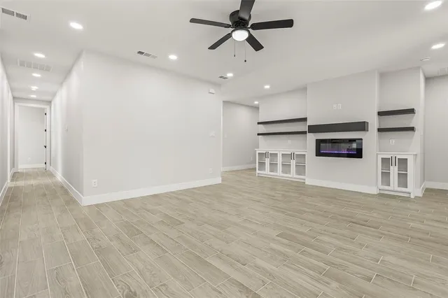 an empty room with wooden floor and a ceiling fan