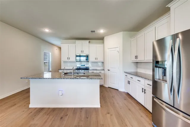 a kitchen with stainless steel appliances granite countertop a refrigerator a stove and a wooden floors