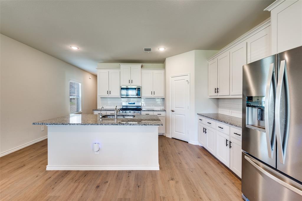 3876 Lyndhurst Avenue Little Elm, TX 75068 - Photo 5 of 25 a kitchen with stainless steel appliances granite countertop a refrigerator a stove and a wooden floors