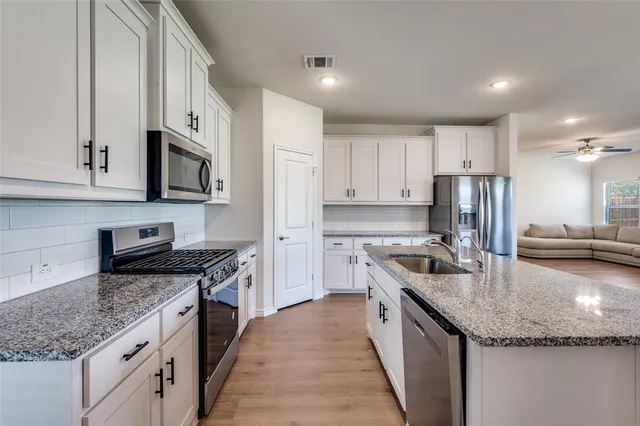 a kitchen with stainless steel appliances granite countertop a sink stove microwave and refrigerator