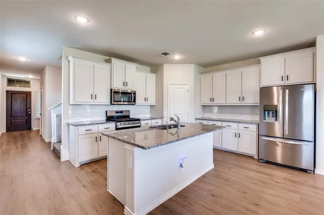 a kitchen with a sink wooden floor and stainless steel appliances
