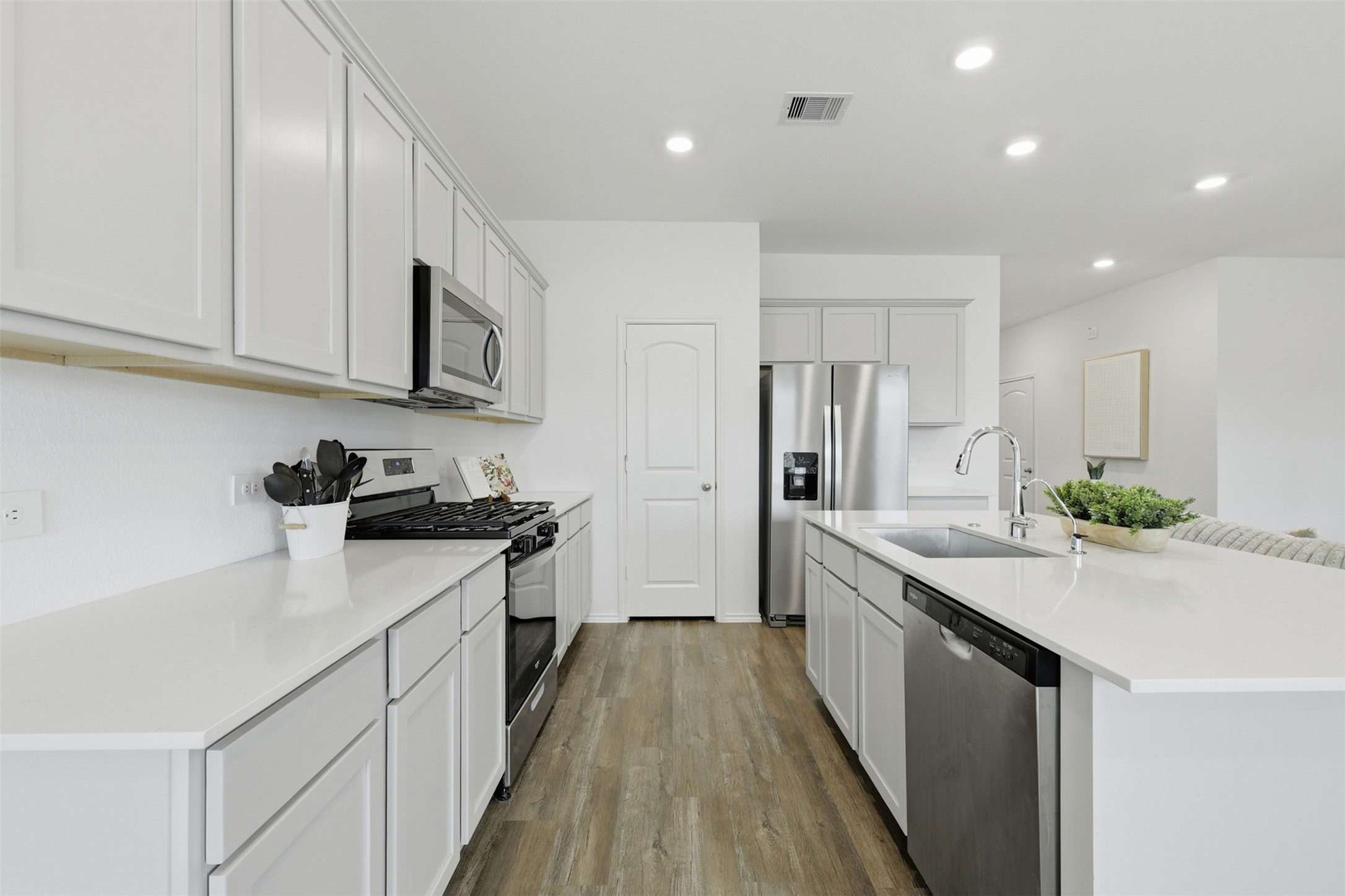 17719 Winfall Drive Crosby, TX 77532 - Photo 16 of 47 Bright, modern kitchen with sleek white cabinets, stainless steel appliances, and light flooring. Features a spacious island with a sink and ample counter space for cooking and entertaining.