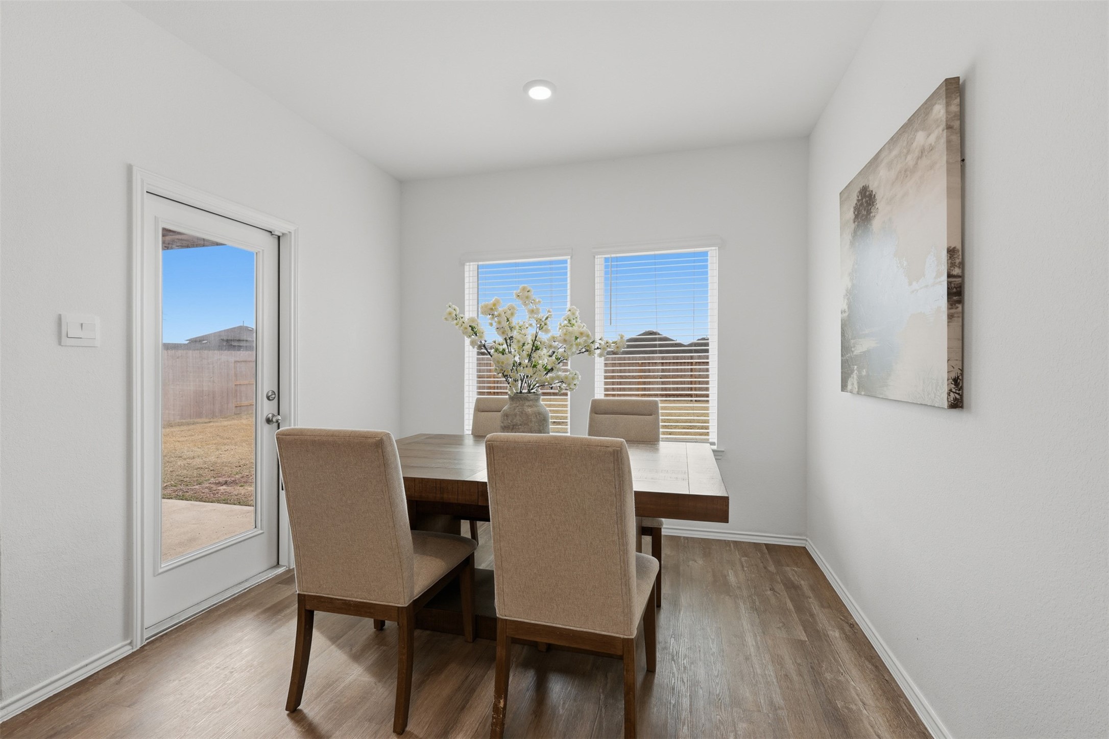 17719 Winfall Drive Crosby, TX 77532 - Photo 20 of 47 Bright dining area with large windows, light flooring, and a cozy table setup. Features a door to the backyard, offering ample natural light and a welcoming atmosphere.