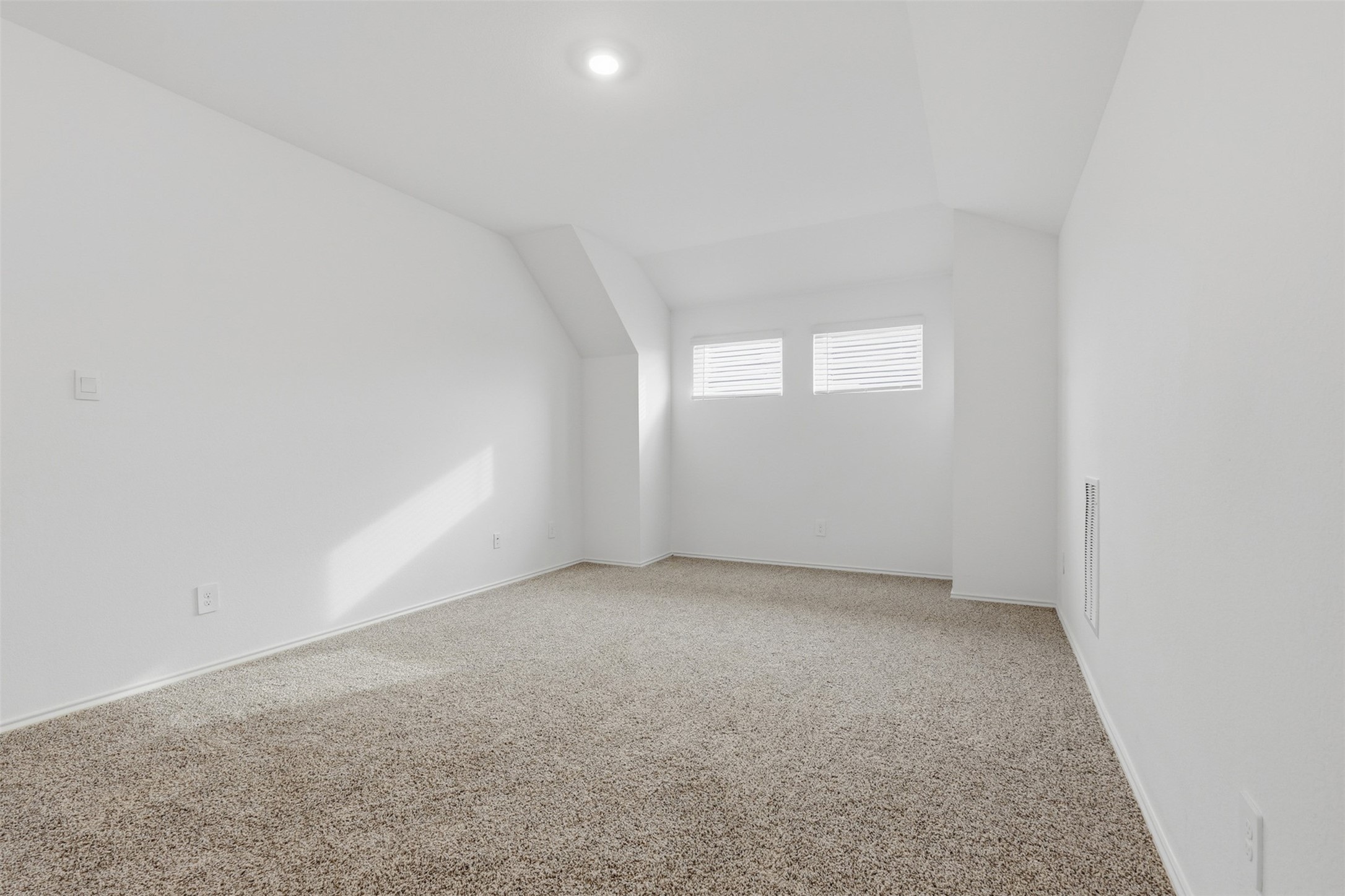 17719 Winfall Drive Crosby, TX 77532 - Photo 27 of 47 This game room features clean white walls and plush carpet flooring, with natural light streaming through two small windows. Its angled ceiling adds architectural interest, making it a cozy and versatile space.