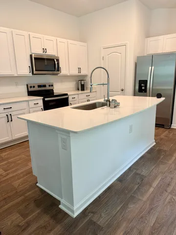 a kitchen with kitchen island a sink a stove and a microwave